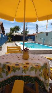 een tafel met een parasol naast een zwembad bij Casa Temporada à Beira da Praia in Maricá