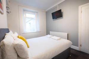 a bedroom with a white bed with a tv on the wall at 5-Bedroom home - Ideal for groups working away from home in Swansea