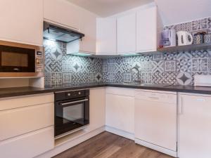 una cocina con armarios blancos y electrodomésticos blancos en Appartement Plagne Villages, 2 pièces, 6 personnes - FR-1-181-2624, en La Plagne Tarentaise