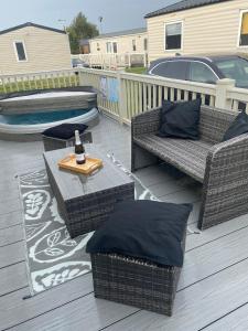 a patio with wicker chairs and a table with a bottle of wine at Lancaster Crescent Hot Tub Hideaway in Tattershall