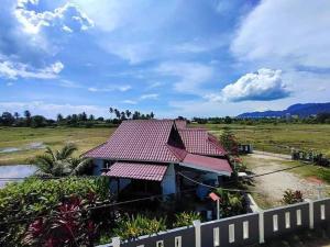 a house with a red roof in a field at Langkawi Homestay Bunga Padi in Kuah