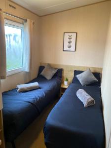 two beds in a room with a window at Lancaster Crescent Hot Tub Hideaway in Tattershall