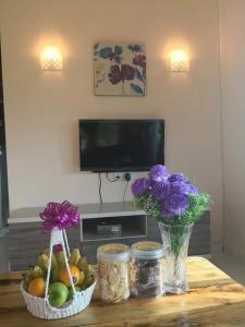 a table with a vase of flowers and a bowl of fruit at Langkawi Homestay Bunga Padi in Kuah