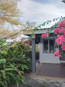 a house with pink flowers and a window at Langkawi Homestay Bunga Padi in Kuah