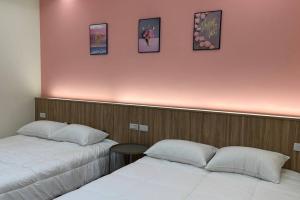 two beds in a room with a pink wall at 包棟陌上花加賴詢問優惠moshang446電麻烤肉switch in Hualien City