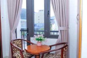 una mesa con un jarrón de flores en el balcón en Ciao Hồng Phúc Hotel, en Quy Nhon