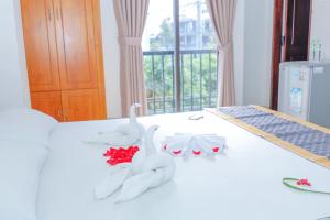 a bed with white towels and flowers on it at Ciao Hồng Phúc Hotel in Quy Nhon