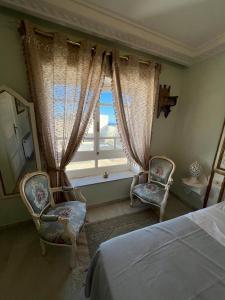ein Schlafzimmer mit 2 Stühlen, einem Bett und einem Fenster in der Unterkunft Dar Yessine Boutique Hôtel in Sousse