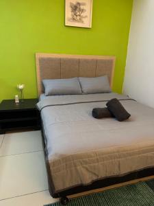 a bed in a room with a green wall at De Vianna Apartment Wakaf Che Yeh in Kota Bharu