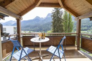 une terrasse couverte avec une table, des chaises et des montagnes dans l'établissement Chasa Stradun 400, à Scuol