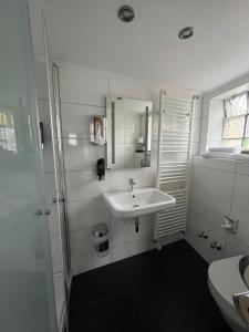 a white bathroom with a sink and a mirror at Hotel 9-enhof in Wuppertal