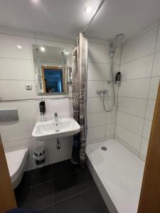 a white bathroom with a sink and a shower at Hotel 9-enhof in Wuppertal