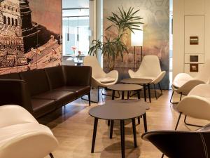 una sala de espera con sofá, mesas y sillas en B&B Hotel Koblenz en Koblenz