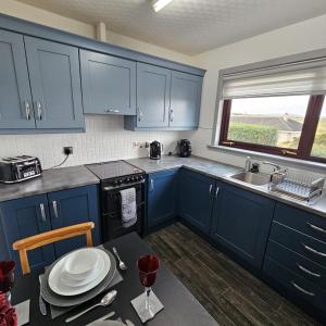 una cucina con armadi blu, tavolo e lavandino di BAYVIEW a Stornoway