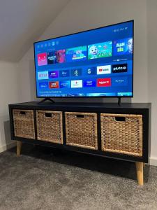 a flat screen tv sitting on a stand with wicker baskets at Pass the Keys Lovely 1-bedroom flat in St Leonards on Sea in Hollington