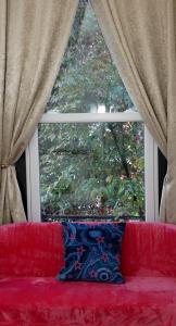 un sofá rojo sentado frente a una ventana en Luxury London house sleeps 13, 2 minutes to metro, en Londres