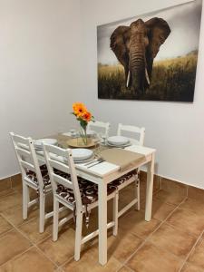 a dining room table with an elephant painting on the wall at Apartamento Las Palomas in Bonares
