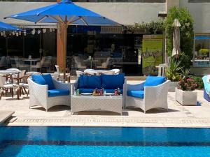 Rivoli Suites and Spa في الغردقة: مسبح وكراسي وطاولة مع مظلة زرقاء