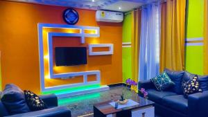 uma sala de estar com um sofá e uma televisão na parede em Favoured Apartment em Kwabenya