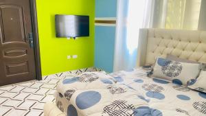 um quarto com uma cama e uma televisão na parede em Favoured Apartment em Kwabenya