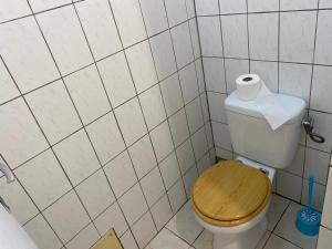 a bathroom with a toilet with a wooden seat and a roll of toilet paper at La Belle Escapade in Quartier du Fond Fleuri