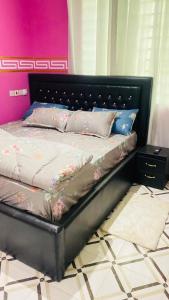 ein Bett mit einem schwarzen Kopfteil in einem Schlafzimmer in der Unterkunft Favoured Apartment in Kwabenyan