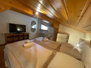 Cette chambre comprend un grand lit blanc et une télévision. dans l'établissement homy Alpine Deluxe Chalet in St Anton im Montafon, à Sankt Anton im Montafon