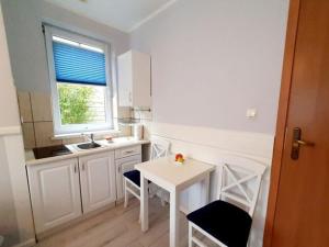 eine Küche mit einem weißen Tisch und Stühlen sowie einem Fenster in der Unterkunft Apartment for 2 people in Mi dzyzdroje in Misdroy