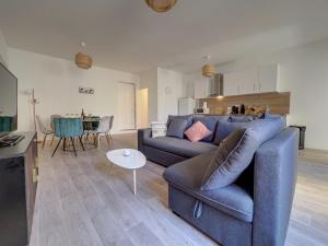 uma sala de estar com um sofá azul e uma mesa em Le "spacieux" en centre ville em Carpentras