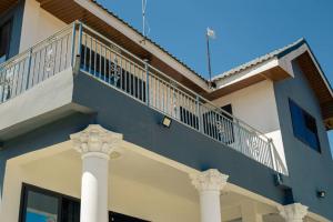 a blue building with a balcony and two columns at Pro CeDi Ventures Self-catering in Kasoa