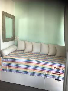 een bank met witte kussens in een kamer met een spiegel bij Appartement face à l'ilet Gosier in Le Gosier
