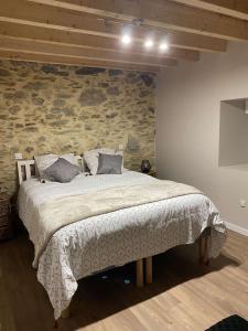1 dormitorio con 1 cama grande y pared de piedra en La Grange du Pradel, en Montredon-Labessonnié