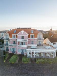 ein großes rosafarbenes Haus mit Balkon davor in der Unterkunft Hotel Bosch En Zee in Domburg