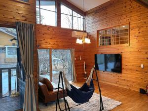 a hammock in a room with wooden walls and a tv at ＨARUNA VILLA 浅間山麓、貸切コテージ、アクセス抜群 in Kita-karuizawa