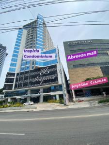 un edificio alto con letreros al lado de una calle en Cozy and Convenient studio unit @ Inspiria condominium, en Davao City