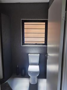 a bathroom with a white toilet and a window at Brae Allen in Hartbeespoort