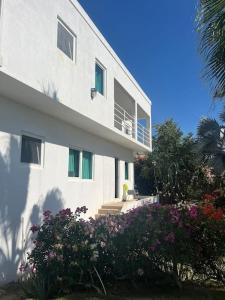 un edificio blanco con flores delante en Whispering Clouds Beach House en Kings Pen