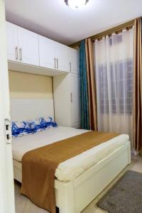- une chambre avec un lit blanc et une fenêtre dans l'établissement JoyfulLiving - 300m to Victoria Mall, near Airport, à Entebbe