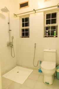 a white bathroom with a toilet and a window at JoyfulLiving - 300m to Victoria Mall, near Airport in Entebbe