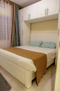 een slaapkamer met een groot bed en witte kasten bij JoyfulLiving - 300m to Victoria Mall, near Airport in Entebbe