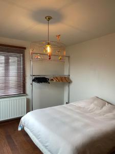 1 dormitorio con cama blanca y lámpara de araña en Appartement aan prachtig rivierenlandschap en Temse