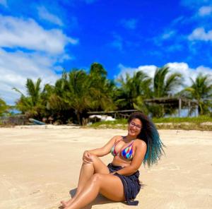une femme en bikini assise sur une plage dans l'établissement Casa em Ilha da Crôa - AL, à Barra de Santo Antônio
