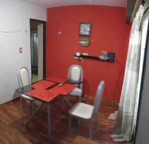 una mesa y sillas en una habitación con una pared roja en Departamento 2 ambientes en Buenos Aires