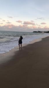 une femme debout sur une plage près de l'océan dans l'établissement Casa em Ilha da Crôa - AL, à Barra de Santo Antônio