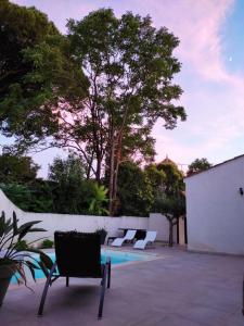een patio met 2 stoelen en een zwembad bij La maison sous les pins in Saint-Laurent-dʼAigouze