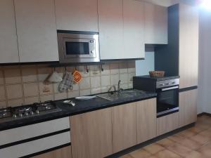 a kitchen with a sink and a microwave and a stove at Casa del Sole in Pitigliano