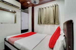a bedroom with a bed with a red pillow at Hotel Memsaab Family Residency in Mumbai