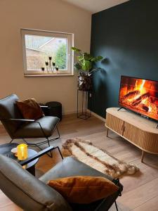 a living room with a flat screen tv and chairs at Luxe Hottub Huisje Bij het Veen op de rand van het Bargerveen Drenthe in Weiteveen