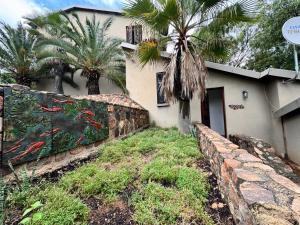 a house with a wall and palm trees in front of it at Aurora Bushbaby 2 in Centurion