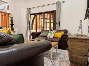 a living room with a leather couch and a table at Aurora Bushbaby 2 in Centurion